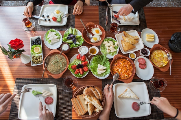 Free photo top view assorted breakfast with omelette and glass of tea and hands of people in serving napkins