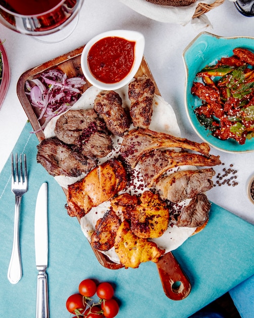 Vista dall'alto di kebab di carne assortiti con spezie cipolle e insalata fresca