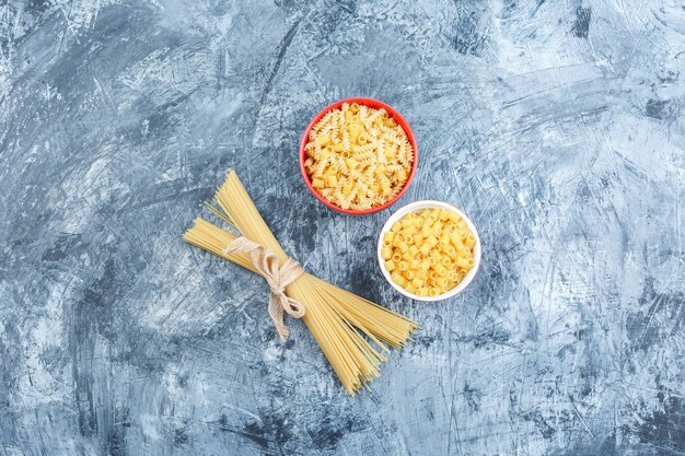 Top view assorted pasta in bowls on grey plaster background. horizontal