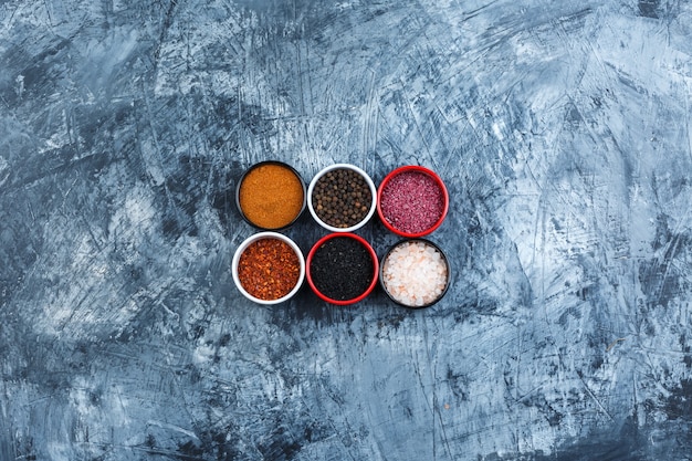 Top view assorted spices in small bowls on grey plaster background. horizontal