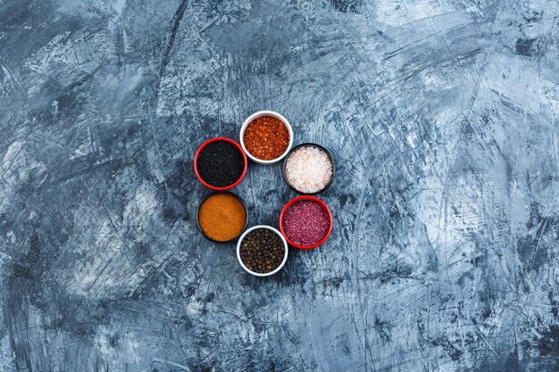 Top view assorted spices in small bowls on grey plaster background. horizontal