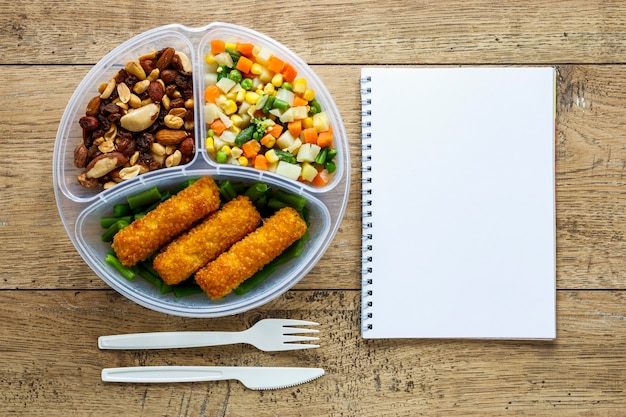 Top view assortment of batch food cooked with empty notebook