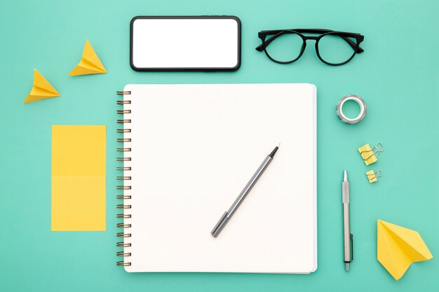 Top view assortment of desk elements with empty notebook and phone