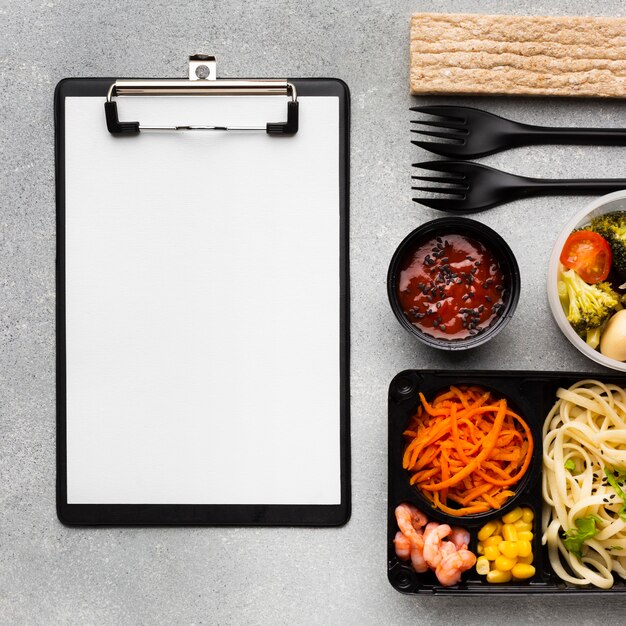 Top view assortment of different foods with empty clipboard