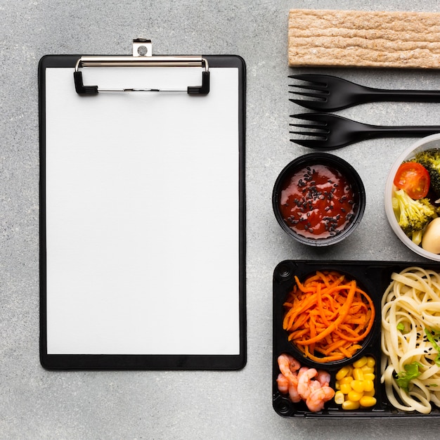 Top view assortment of different foods with empty clipboard