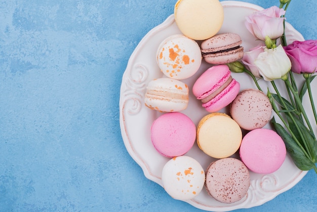 Top view of assortment of macarons on plate with roses