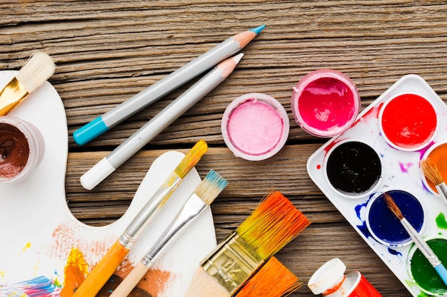 Top view assortment of paint brushes and pencils