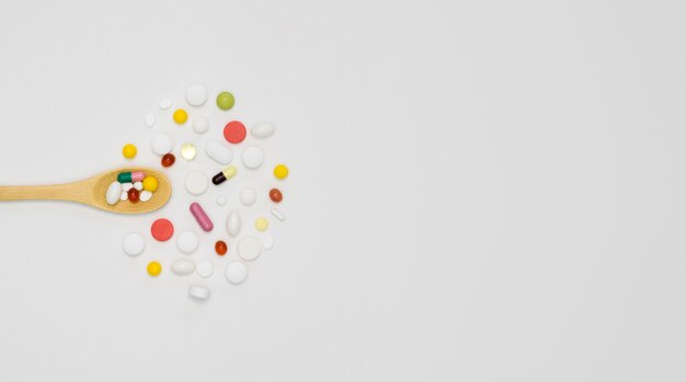 Top view of assortment of pills with spoon and copy space