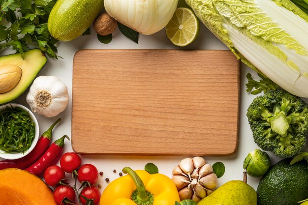 Top view of assortment of vegetables with chopping board