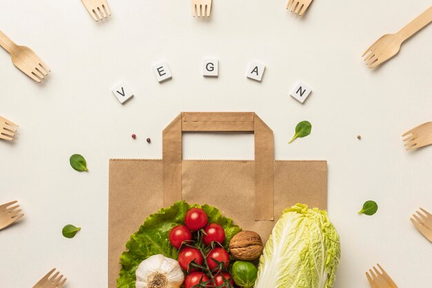 Top view of assortment of vegetables with paper bag and the word vegan