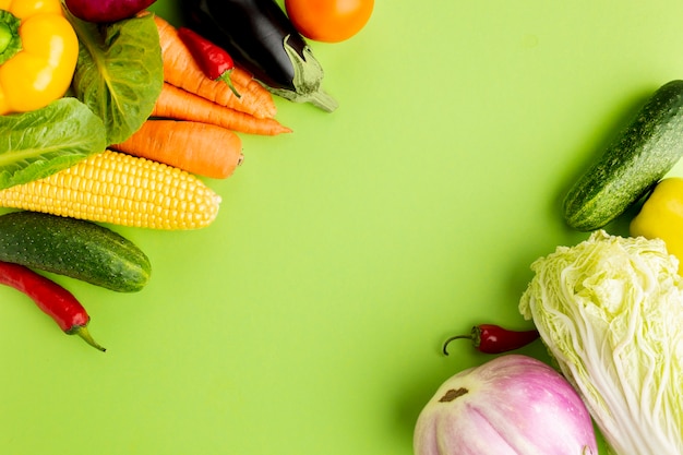 Top view assortment of veggies on green background with copy space