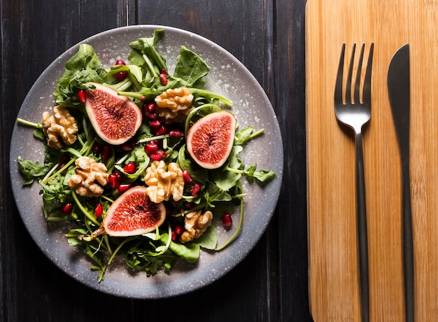 Foto gratuita vista dall'alto di insalata di fichi d'autunno su piatto e posate