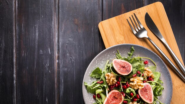 Top view of autumn fig salad on plate with cutlery and copy space