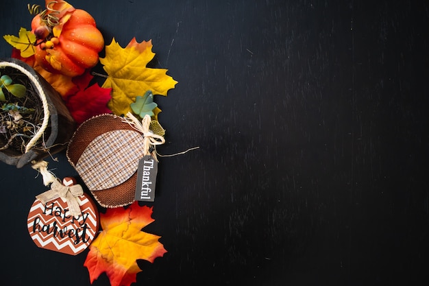 Top view of autumn maple leaves with pumpkin on a black wooden surface