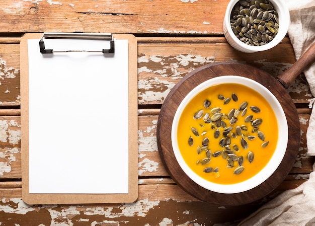 Free photo top view of autumn squash soup with seeds and notepad