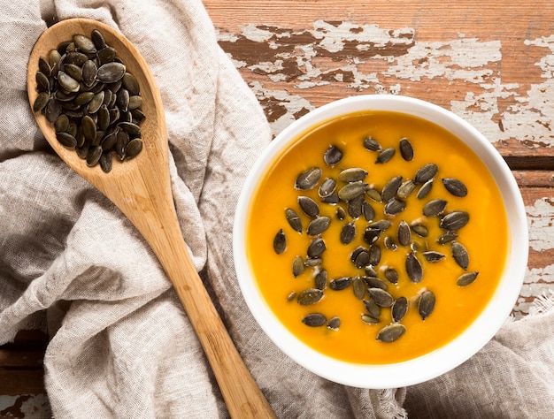 Top view of autumn squash soup with seeds and wooden spoon