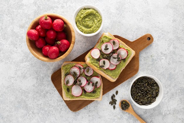 Top view avocado toast with radish and seeds on cutting board