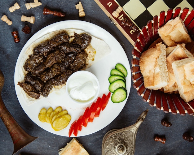 Foto gratuita vista dall'alto di foglie di vite azero dolma servito con verdure allo yogurt e sottaceti