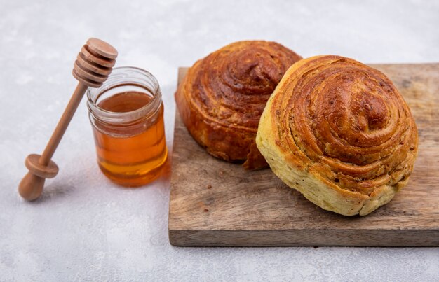 Top view of azerbaijani traditional pastry gogal on a wooden kitchen board with honey on a glass jar on a white background