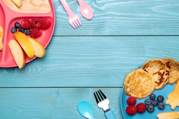 Top view of baby food with blueberries and cutlery