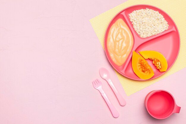 Top view of baby food with fruit and cutlery