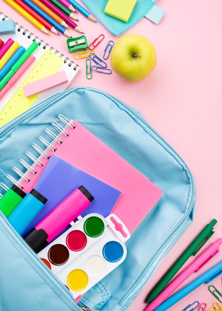 Top view of back to school essentials with backpack and apple