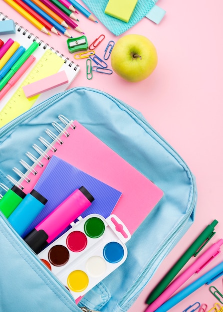 Top view of back to school essentials with backpack and apple