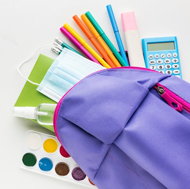 Top view of back to school essentials with backpack and calculator