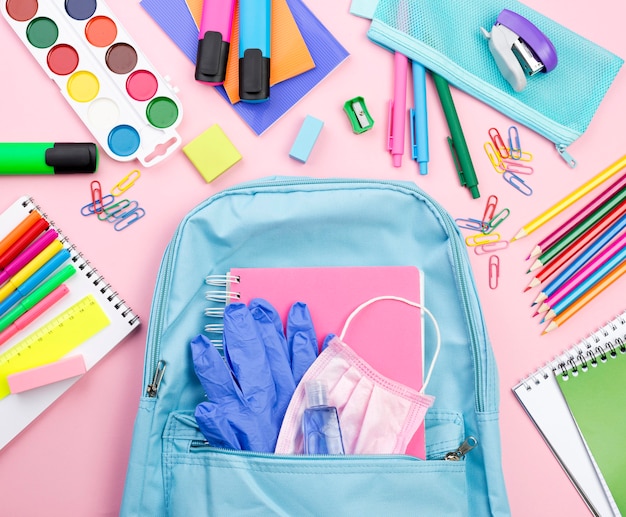 Top view of back to school essentials with backpack and watercolor
