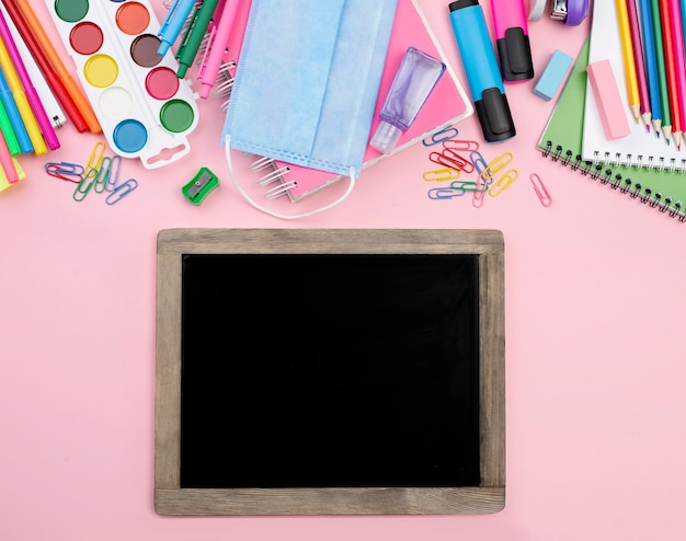 Top view of back to school essentials with blackboard and paper clips