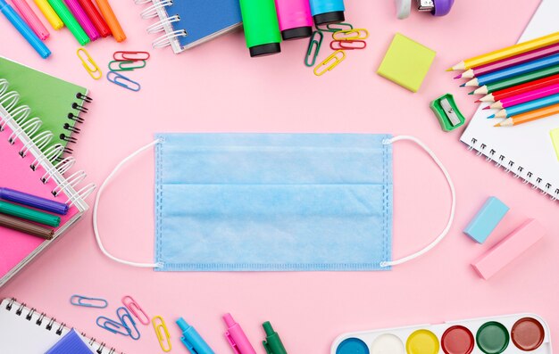 Top view of back to school essentials with medical mask and notebooks