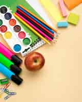 Foto gratuita vista dall'alto di ritorno a scuola di articoli di cancelleria con mela e matite colorate