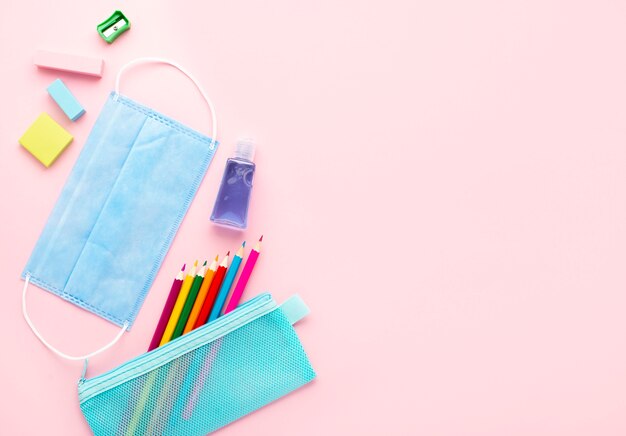 Top view of back to school stationery with medical mask and colorful pencils