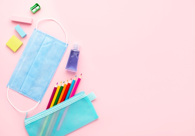 Top view of back to school stationery with medical mask and colorful pencils