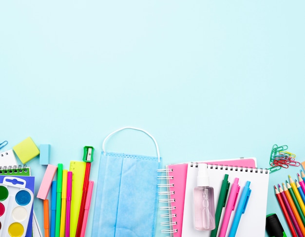 Top view of back to school stationery with medical mask and copy space