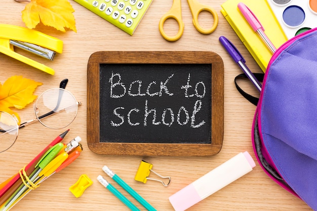 Top view of back to school supplies with blackboard and backpacl