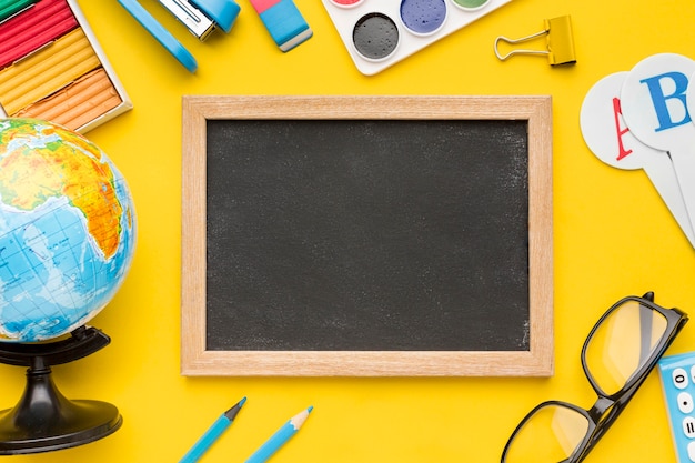 Top view of back to school supplies with blackboard and glasses