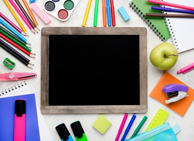 Top view of back to school supplies with colorful pencils and blackboard