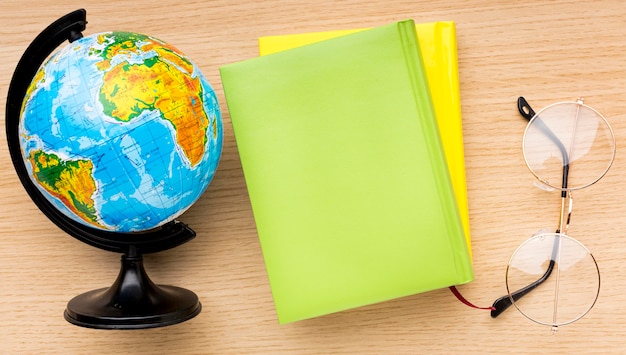 Top view of back to school supplies with glasses and globe