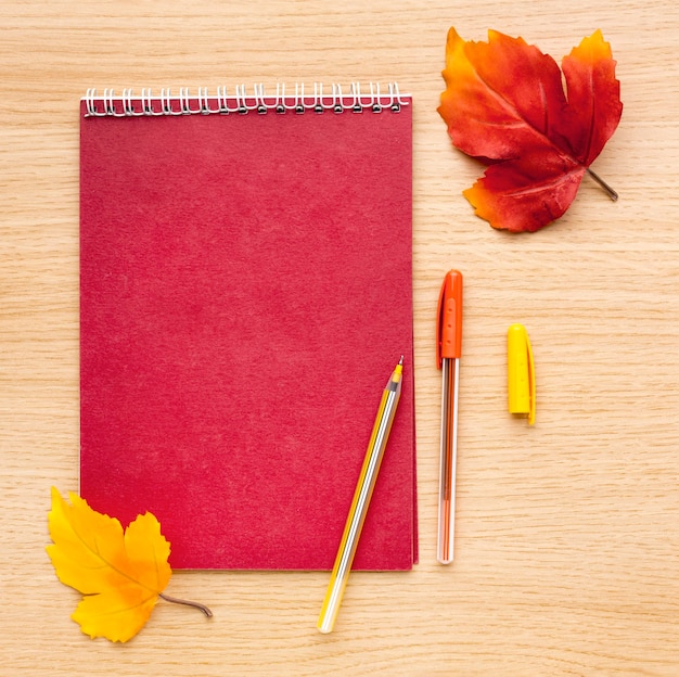 Top view of back to school supplies with leaves and notebook