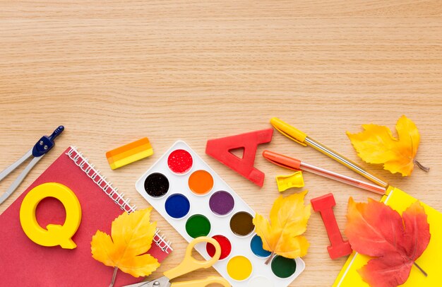 Top view of back to school supplies with leaves and notebook