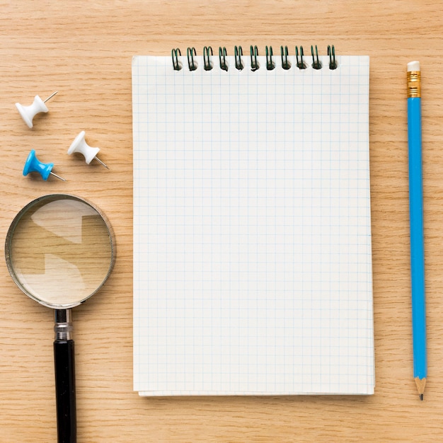 Top view of back to school supplies with notebook and magnifying glass