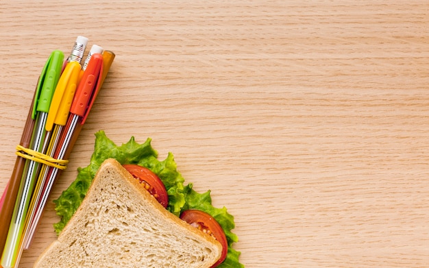 Top view of back to school supplies with sandwich and pencils
