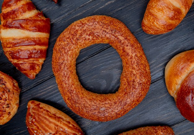 Top view of bagel and other bakery products around on wooden background