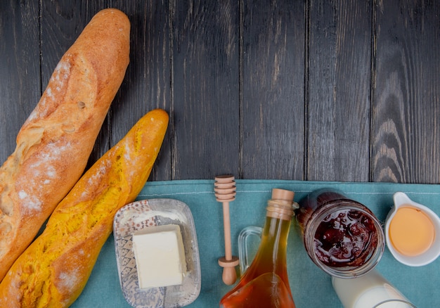 Vista superiore delle baguette con il latte di burro dell'inceppamento di fragola sul panno blu e sul fondo di legno