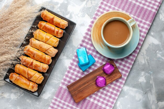 Top view of baked bangles delicious pastries along with milk coffee on light desk, sweet pastry cookie sugar bake