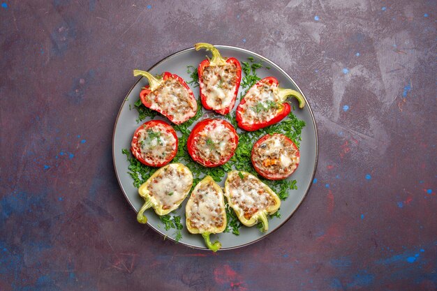 Top view baked bell-peppers with cheese greens and meat inside plate on a dark background bake meal dinner dish food