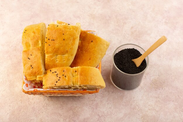 A top view baked bread hot tasty fresh sliced inside bread bin along with pepper on pink