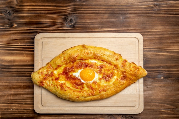 Top view baked bread with cooked egg on the brown wooden surface bread bun food eggs breakfast dough