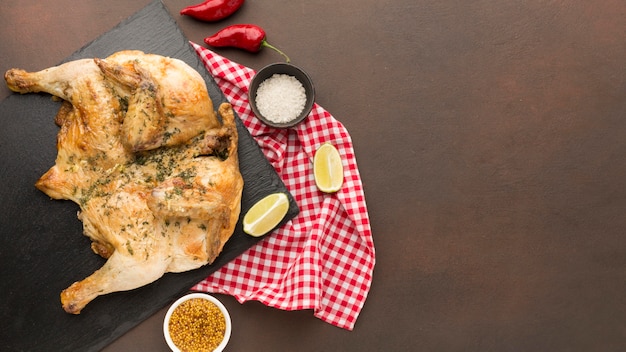 Top view baked chicken on cutting board with condiments and copy-space